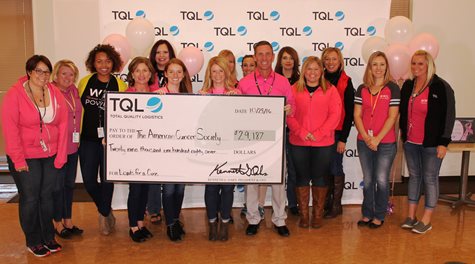 Employees In Pink Shirts Smiling With A Giant Check