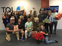 TQL Employees Smiling With Christmas Gifts for CASA