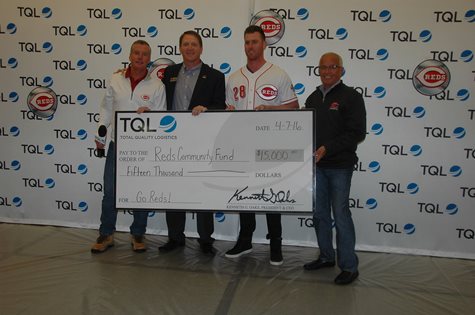 Three Employees And A Reds Player Smiling In Front Of A TQL Background With A Giant Check