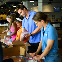 TQL employees and retired Bengals player Sam Hubbard fill backpacks with school supplies during a TQL Cares volunteer event benefiting Cincinnati-area students.