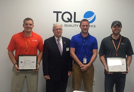 Men holding awards in front of TQL logo