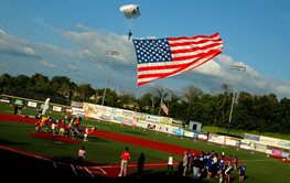 Parachuter with American flag landing on a baseball diamond