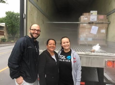 Three people standing in front of open truck trailer