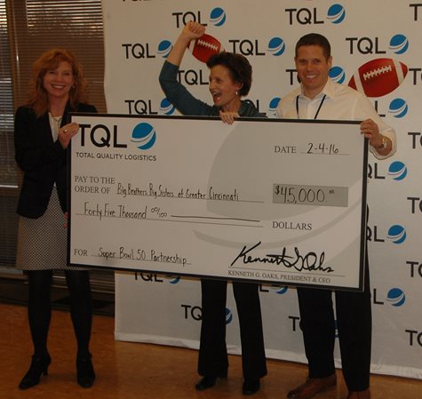 Three People Holding A Large TQL Check And Celebrating