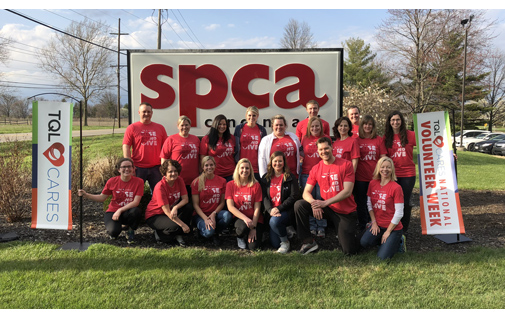 TQL Employees Posing In Front Of A SPCA Sign While Wearing Red