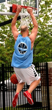 Man hanging on basketball rim after dunking