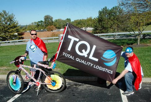 Two men with decorated bike and TQL flag