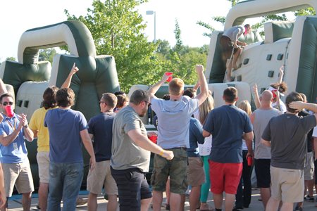 Man on inflatable obstacle course and crowd cheering