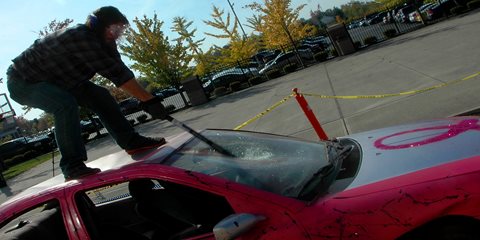 Person smashing car windshield with baseball bat