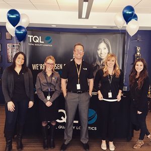 People posed in front of TQL banner