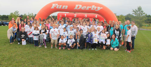 A Crowd Of People Smiling In Front Of A Front Derby Inflatable Sign