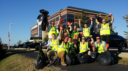 People in safety vests holding garbage bags in front of TQL building