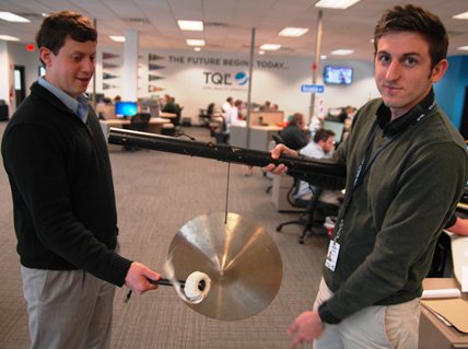 Two men holding and ringing a gong