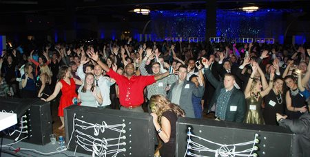 Large Group Of People Standing And Cheering At The End Of Year Party