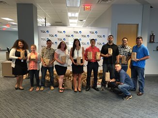 People holding paper bags behind TQL backdrop