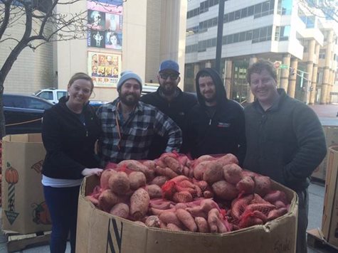 Five Employees Smiling Behind A Cardboard Container Of Potatoes