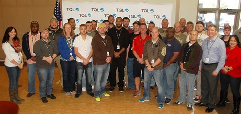 Employees Smiling In Front Of An American Flag And TQL Sign