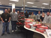 Group Of People Standing With Christmas Presents And A Tree