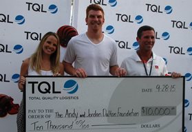 Andy Dalton and TQL employees holding check in front of TQL backdrop