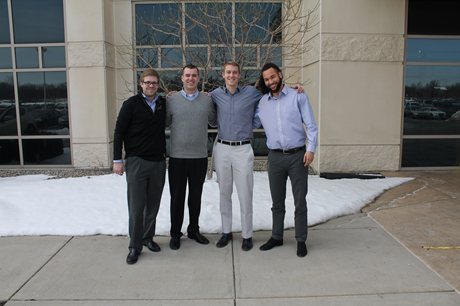 Four men posing outside building