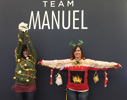 Two Women Dressed As Christmas Items In Front Of A Grey Team Manuel Wall