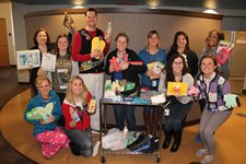 People Posing With Items For YWCA Women's Domestic Violence Shelter