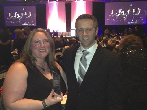 Two People Posing At A Conference While Holding An Award