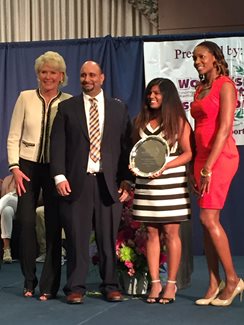 four people in formal wear holding a plaque